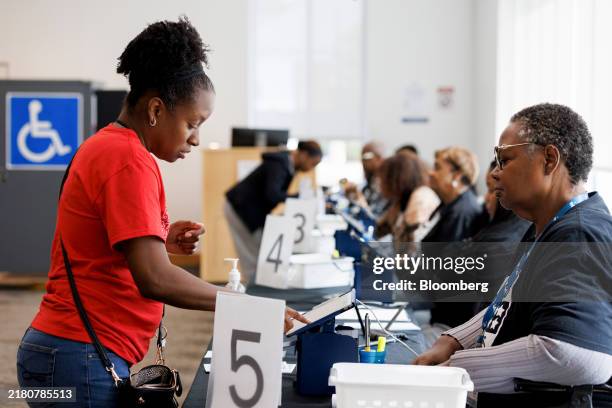 Poll workers check in a voter at a polling location inside Metropolitan Branch Library during early voting in Atlanta, Georgia, US, on Sunday, Oct...