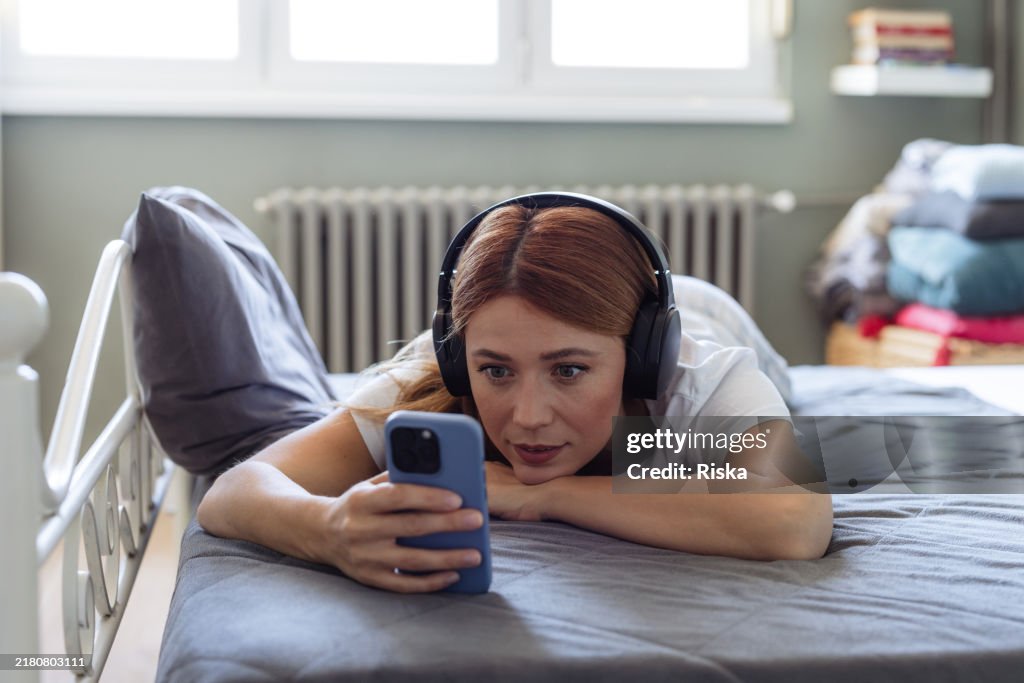 Donna che si rilassa a letto e guarda il telefono