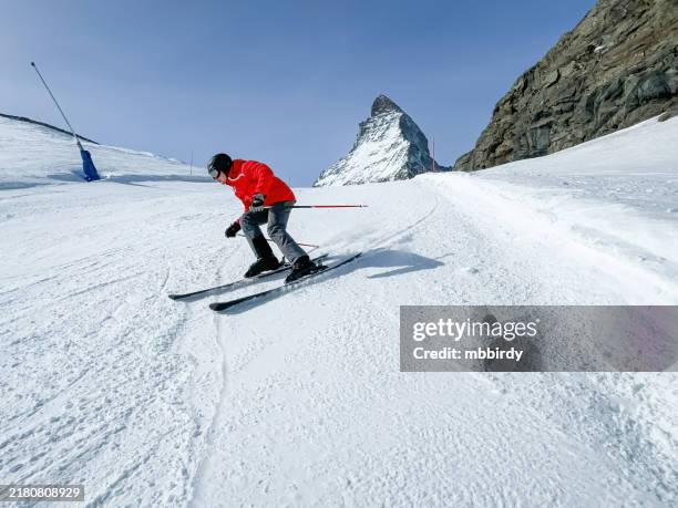 young skier skiing downhill at zermatt ski resort, switzerland - abfahrtslauf stock-fotos und bilder