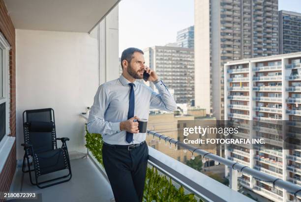 gay man ready for work at the balcony of city apartment - toronto coffee stock pictures, royalty-free photos & images