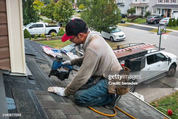 roofer worker installs new roof nail gun - telhado imagens e fotografias de stock