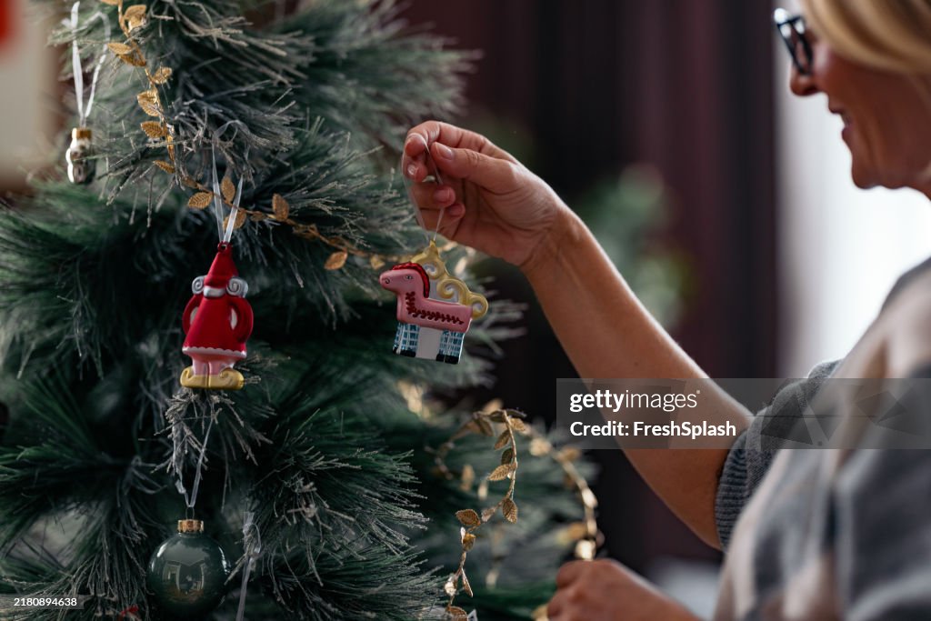 Frau, die einen Weihnachtsbaum mit festlichem Schmuck schmückt
