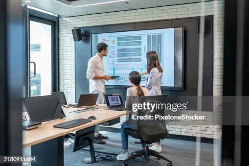 Man software developer presenting the Mobile Application Architecture Diagram on the large screen to developer team in meeting room. Man software developer presenting the Mobile Application Architecture Diagram on the large screen to developer team in meeting room.