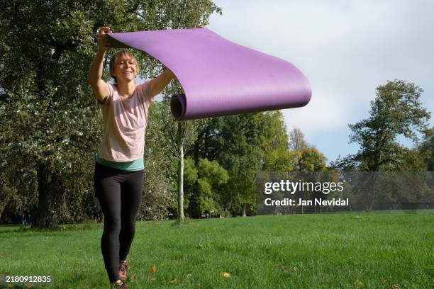 unrolling yoga mat in preparing for self-care outdoors - positioning stock pictures, royalty-free photos & images