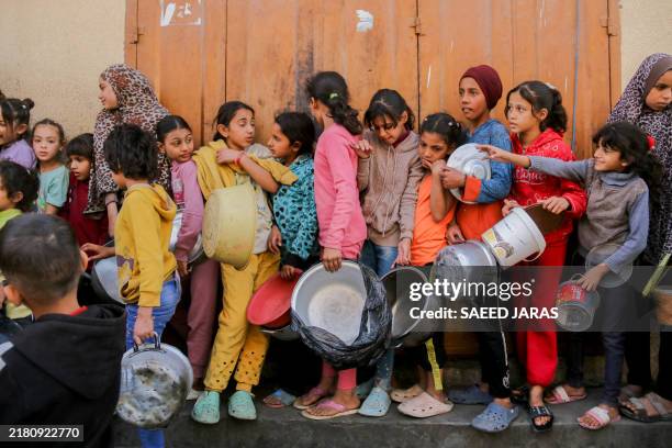 Children stand in a long line, waiting for food distribution in the Palestinian territories on October 25, 2024. Displaced residents face daily...