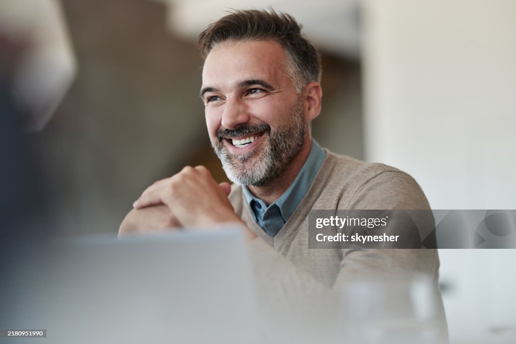 Glücklicher Geschäftsmann im mittleren Erwachsenenalter, der im Büro genießt.