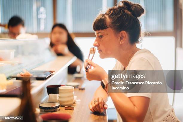 woman tourist eating sushi, omakase restaurant - bar à sushis photos et images de collection