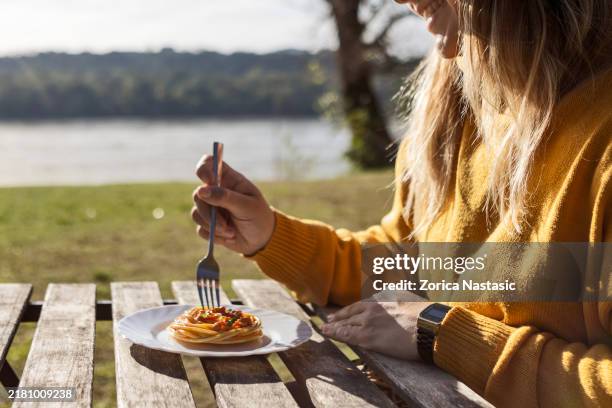 woman eating spaghetti by the river - autumn lake chair stock pictures, royalty-free photos & images