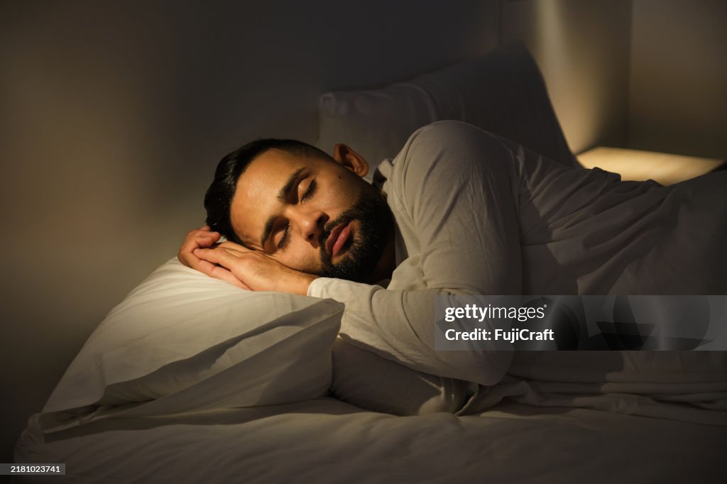 Young man sleeping peacefully in his bed at night