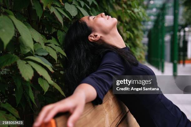young businesswoman relaxing on bench in urban park, breathing fresh air - park bench stock pictures, royalty-free photos & images