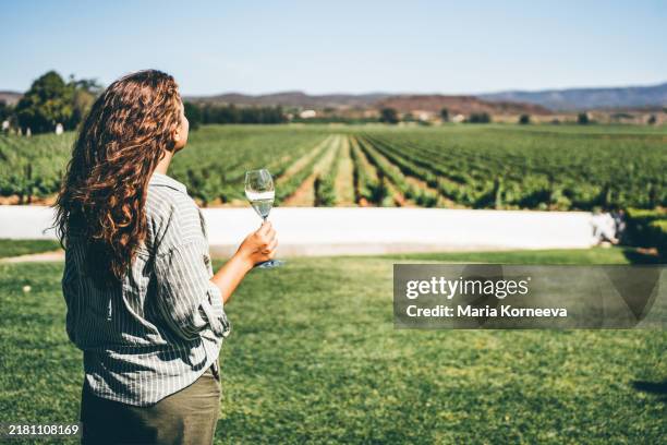 wine tasting in a winery. woman drinking white wine while standing at vineyard. - south africa stock pictures, royalty-free photos & images