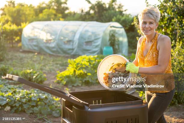 a woman is emptying food waste into a garden composter - compostable stock pictures, royalty-free photos & images
