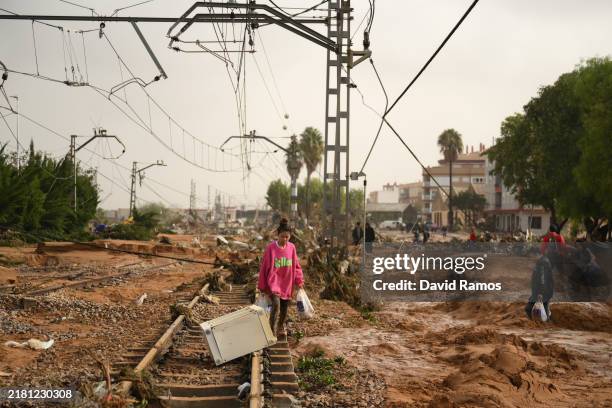 Woman walks along train tracks covered debris after flash-flooding hit the region on October 30, 2024 in Valencia, Spain. Spanish authorities said on...