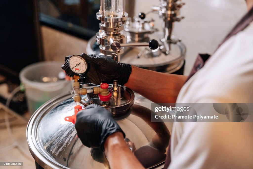 Asian brewer preparing equipment for brewing craft beer in a rural brewery