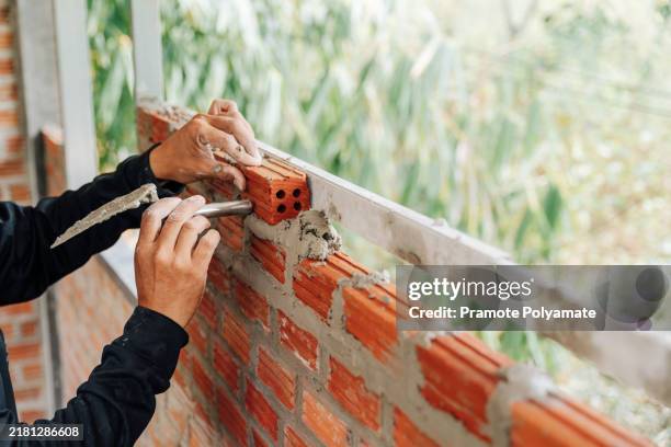 a bricklayer carefully placing bricks to form a sturdy wall at a construction site. - bricklayer stock pictures, royalty-free photos & images
