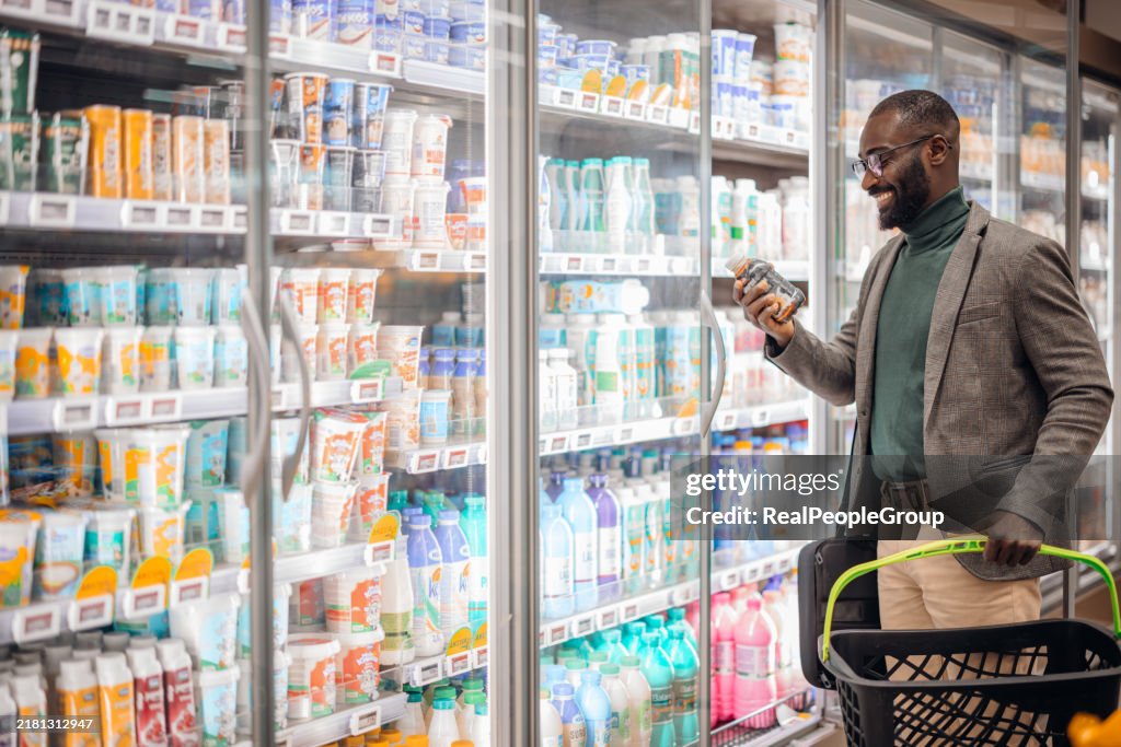 Smiling Man Shopping in Supermarket Dairy Aisle