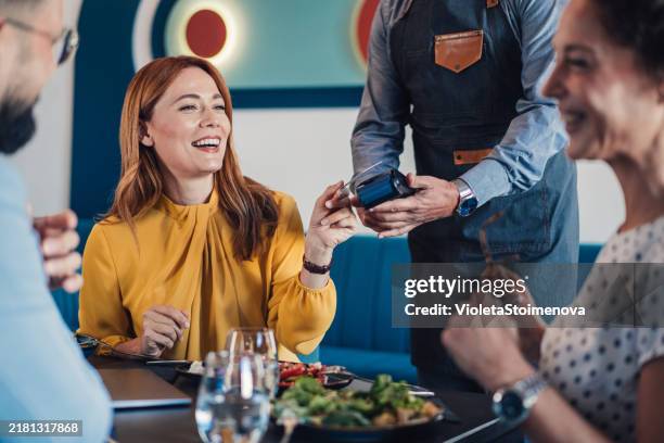 geschäftsfrau, die während des mittagessens mit den kollegen mit kreditkarte bezahlt. - bezahlen stock-fotos und bilder
