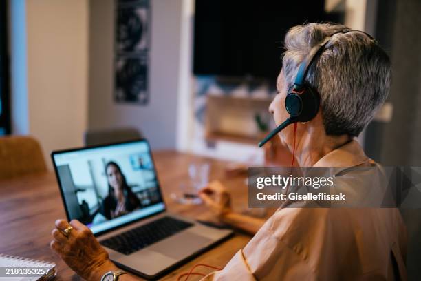 geschäftsfrau mit einem videoanruf im büro - eine seniorin allein stock-fotos und bilder
