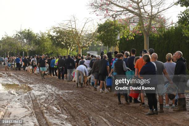 People line up to collect water from a broken pipe after flooding hit large parts of the country on October 31, 2024 in the Paiporta municipality of...