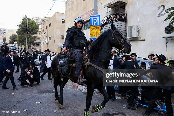 Horse-mounted Israeli policeman disperses ultra-Orthodox Jewish protesters during a demonstration against conscription in Jerusalem on October 31,...