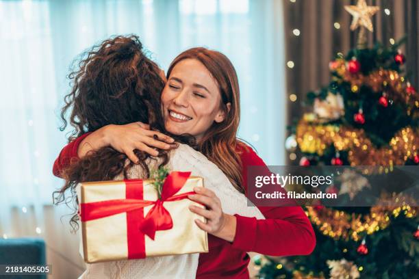 female friends exchanging christmas gift - exchanging gifts stock pictures, royalty-free photos & images