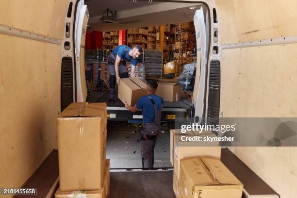 happy warehouse workers unloading boxes in storage room. - loading boxes stock pictures, royalty-free photos & images