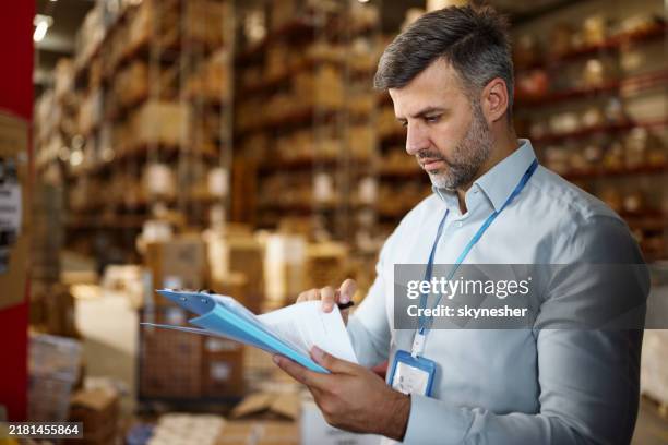 male manager going through plans in distribution warehouse. - product test stockfoto's en -beelden