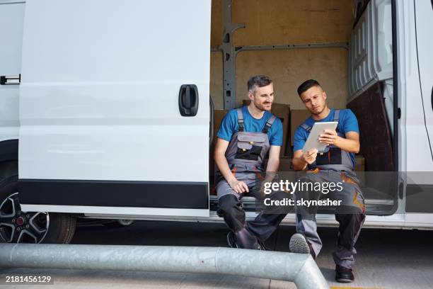fattorini che lavorano sul touchpad vicino al furgone. - veicolo terrestre commerciale foto e immagini stock