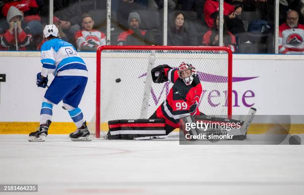 eishockey-torwart blockt einen intensiven torschuss ab - eishockey tor stock-fotos und bilder