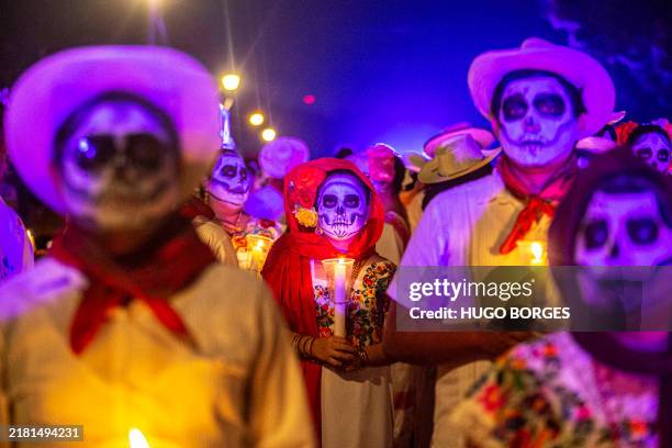 People with painted faces and clad in regional Mesrizo clothing take part in a procession representing The Walk of the Souls, which is the arrival of...
