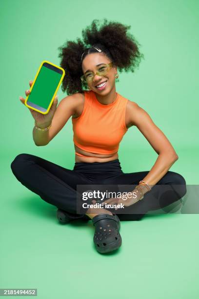 portrait of excited young woman holding phone - showing stock pictures, royalty-free photos & images