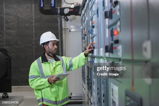 trabalhador técnico trabalhando no quadro de distribuição na estação elétrica. - equipamento elétrico equipamento industrial - fotografias e filmes do acervo
