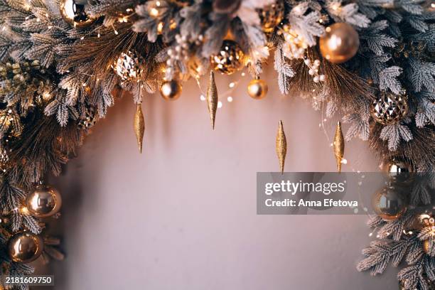decorated christmas arch with snow-covered fir branches and gold toys: balls and icicles in sparkles. white, silver, grey and golden colors. concept of new year and christmas coming. new year's decorations for photo shoots and home life. place for text - floral garland stock pictures, royalty-free photos & images