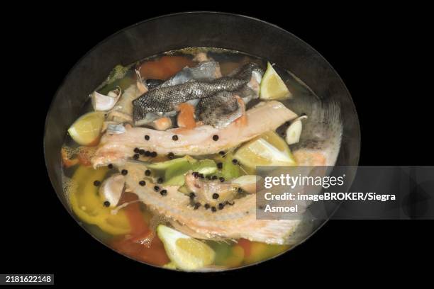 cooked fish stock of a salmon trout with lemons, peppercorns and paprika, food photography with black background - bollito foto e immagini stock