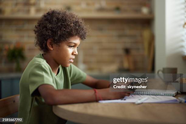 black boy using mobile phone during his homework at home. - innocence stock pictures, royalty-free photos & images