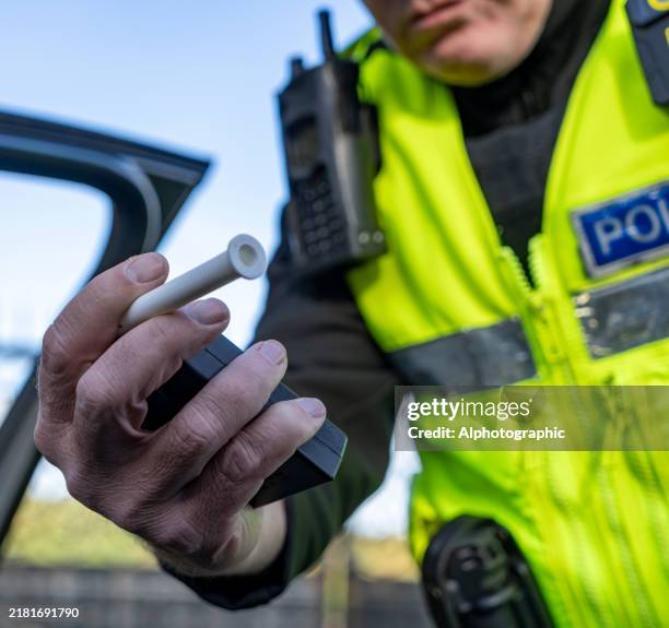 uk police officer holding a breathalyser - police force stock pictures, royalty-free photos & images