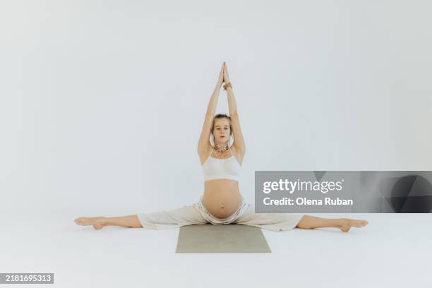 pregnant young woman doing cross twine in a white setting. - acrobatic activity stock pictures, royalty-free photos & images