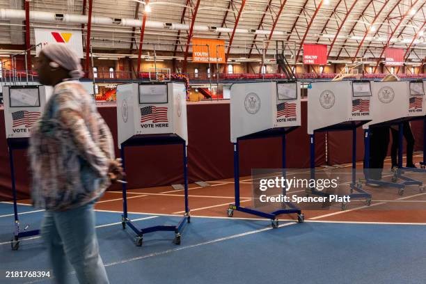 Poll worker walks by voting booths as New Yorkers participate in early voting at a polling site in Brooklyn on October 29, 2024 in New York City. As...