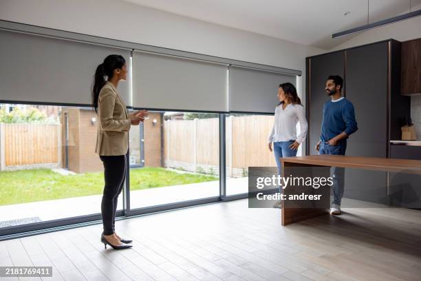 agent immobilier utilisant une télécommande pour baisser les stores d’une maison lors d’une visite - moteur électrique photos et images de collection