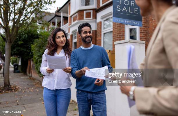 real estate agent handling the blueprints of a house for sale to a couple - house stock pictures, royalty-free photos & images