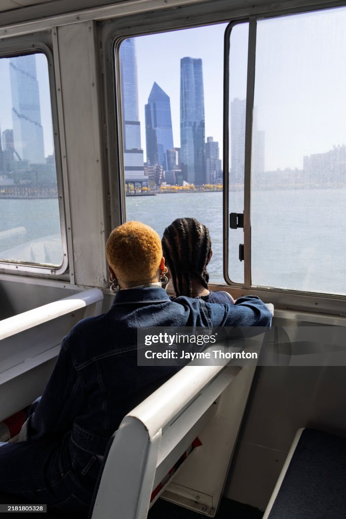 Medium shot rear view female couple looking out window of ferry to city
