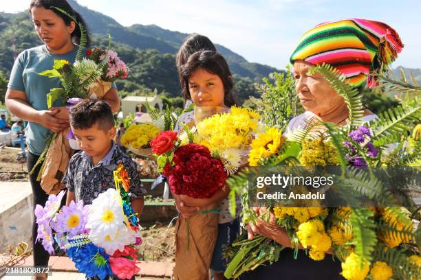 An indigenous woman dressed as 'Panchita' accompanied by her granddaughters and daughters place flowers on the graves of their relatives during the...