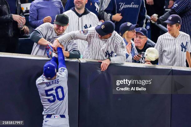 Fans Austin Capobianco and John Peter interfere with Mookie Betts of the Los Angeles Dodgers as he attempts to catch a fly ball in foul territory...