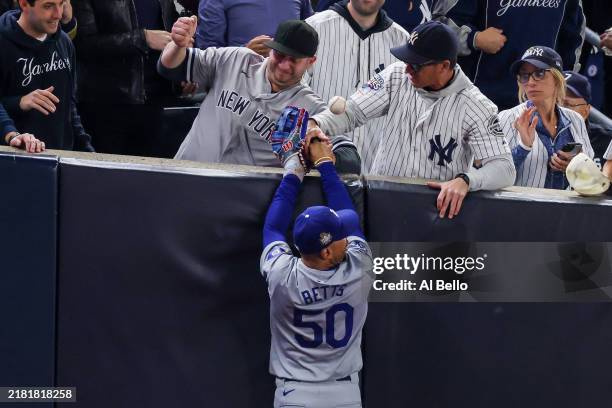 Fans Austin Capobianco and John Peter interfere with Mookie Betts of the Los Angeles Dodgers as he attempts to catch a fly ball in foul territory...