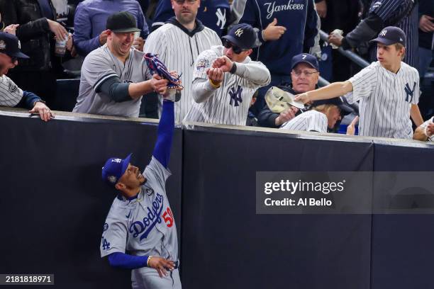 Fans Austin Capobianco and John Peter interfere with Mookie Betts of the Los Angeles Dodgers as he attempts to catch a fly ball in foul territory...