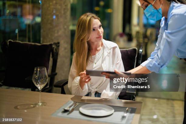 restaurant waitress providing a digital tablet menu to a female customer, highlighting tech-savvy dining and the engaging, personalized service at contemporary dining establishments. - ordering dinner stock pictures, royalty-free photos & images