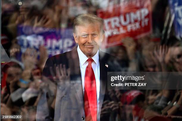 Behind bulletproof glass, former US President and Republican presidential candidate Donald Trump arrives to speak during a campaign rally at Gastonia...