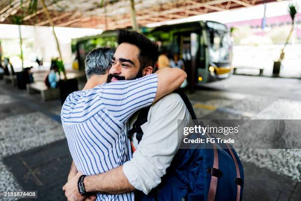 joven abrazando a su novio en la estación de autobuses - estación de autobús fotografías e imágenes de stock