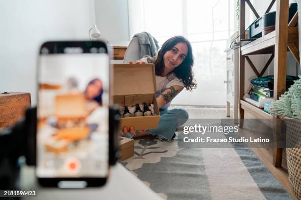 giovane donna che mostra la scatola in live streaming a casa - social media marketing foto e immagini stock