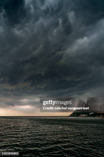 low angle view of storm clouds above sea during sunset - cielo dramático fotografías e imágenes de stock